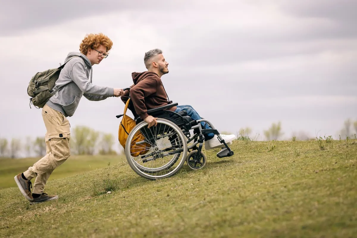 Mies työntää pyörätuolissa olevaa henkilöä