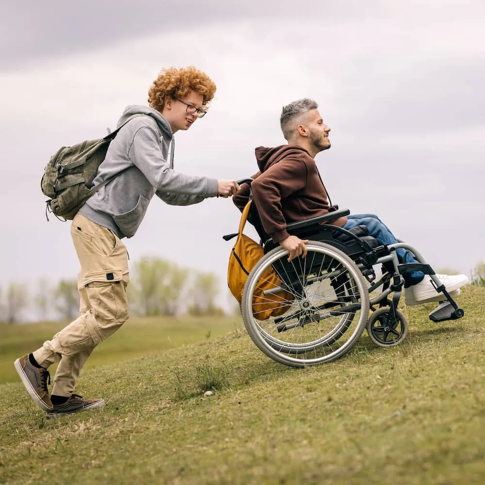 Mies työntää pyörätuolissa olevaa henkilöä